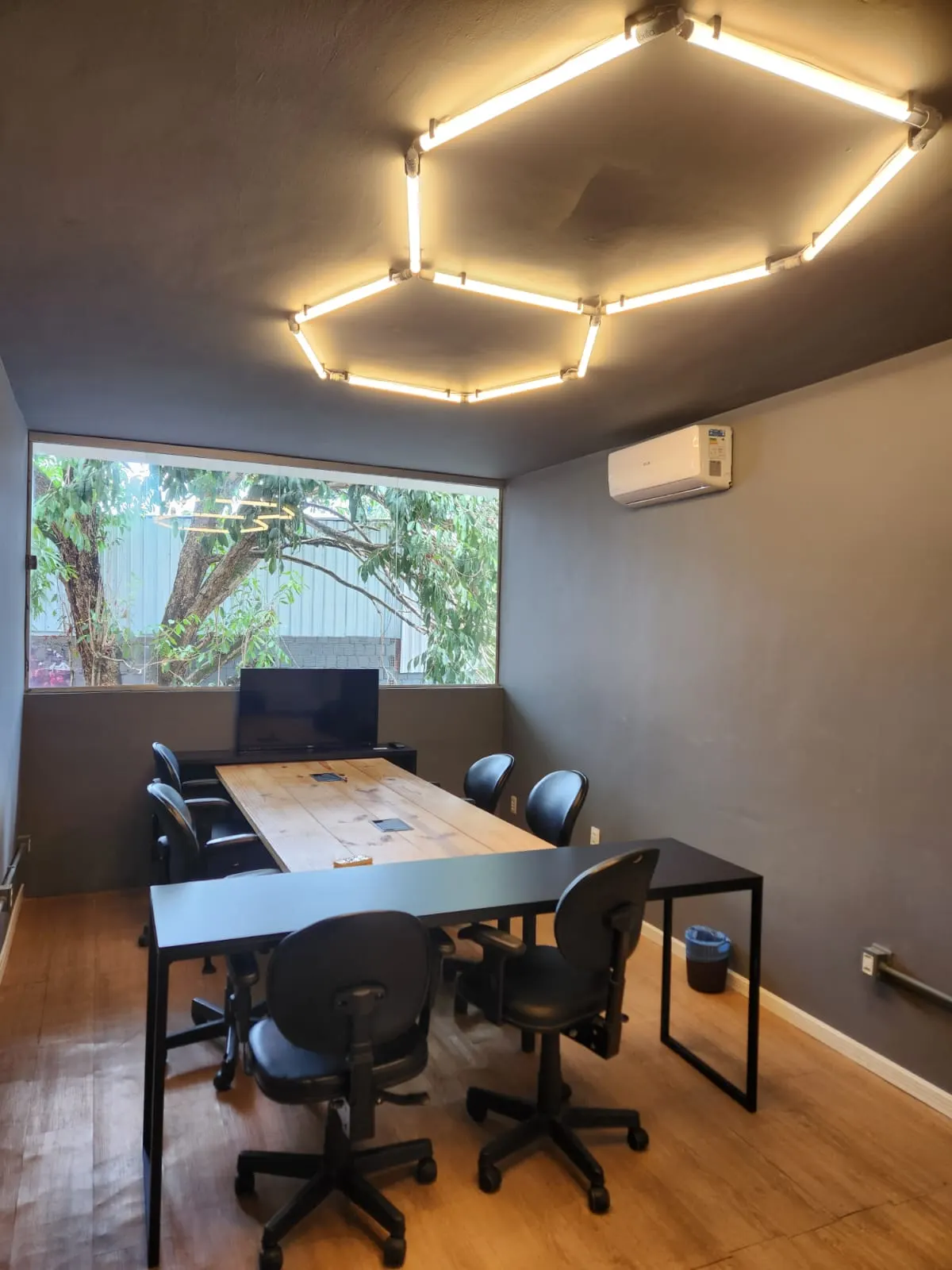 Sala de reunião do Clubjob com luminária hexagonal e janela para as árvores