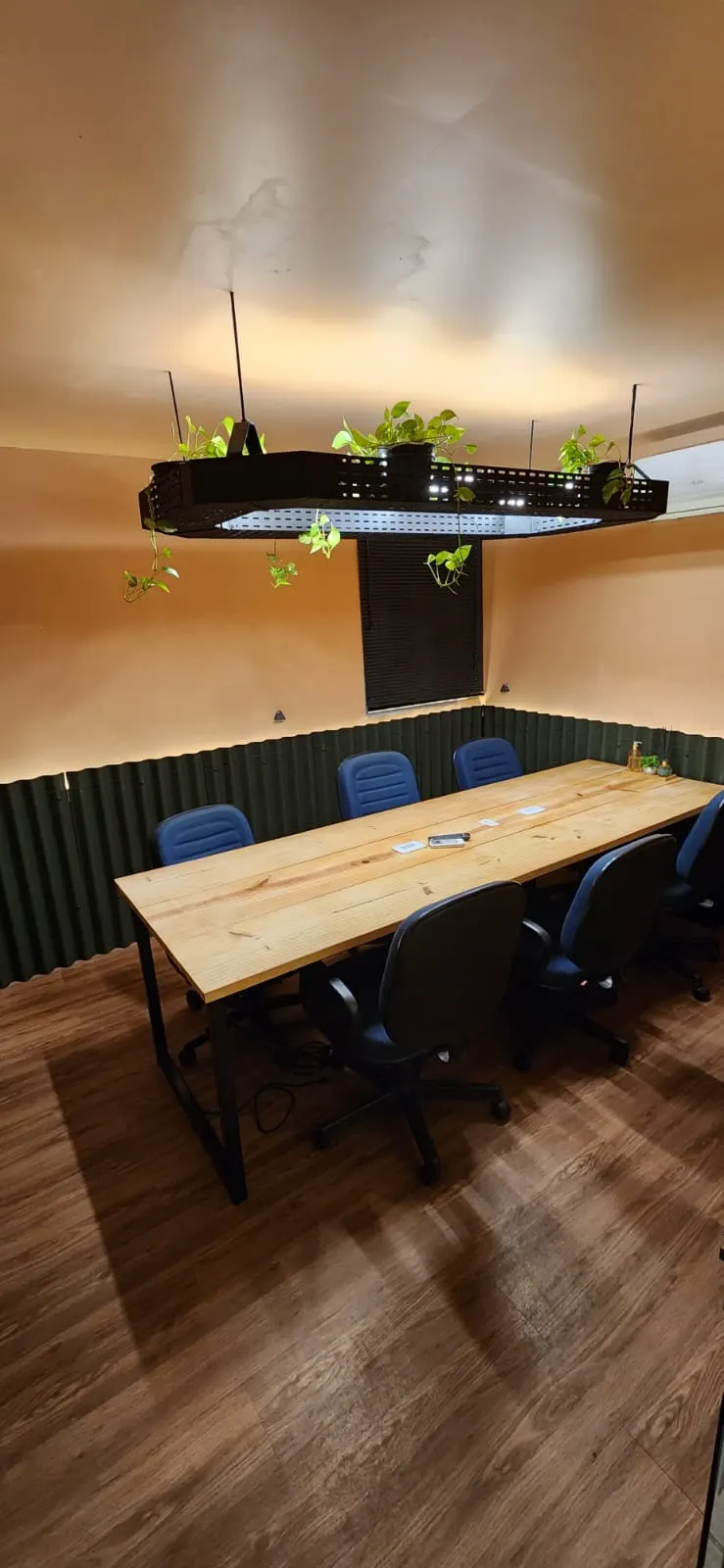 Sala de reunião do Clubjob com mesa de madeira e plantas no teto